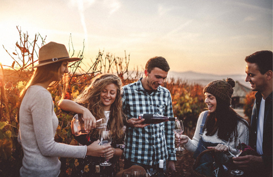 Vigneto autunnale con persone sorridenti che si versano il vino