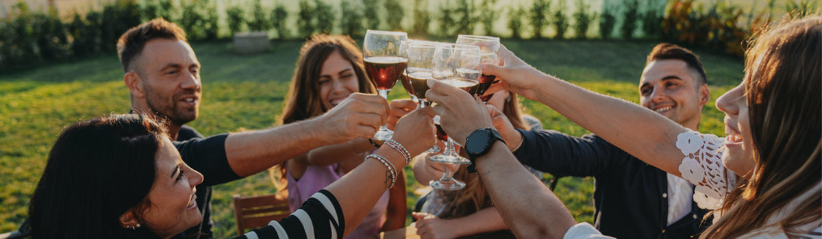 Benvenuti da Vinoreale. Le persone sono sedute all'aperto e brindano insieme con i calici di vino.